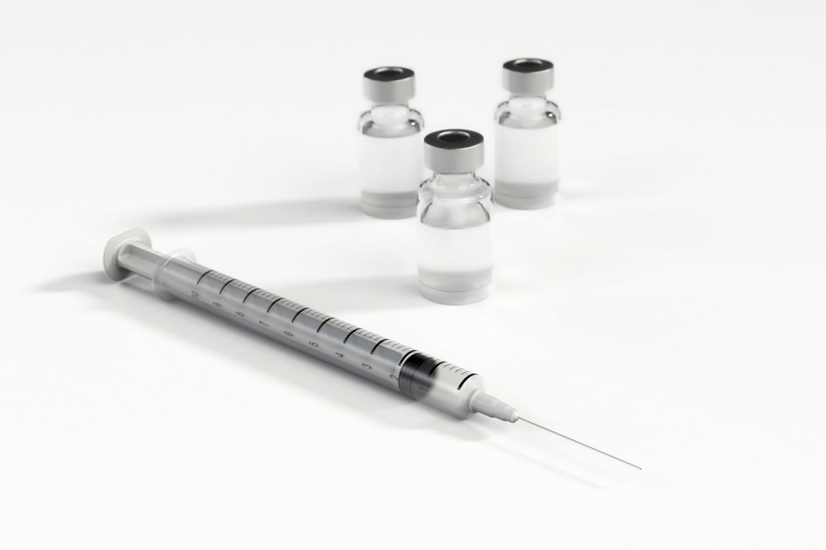 The image shows a syringe and three small vials/bottles, all placed on a white background.