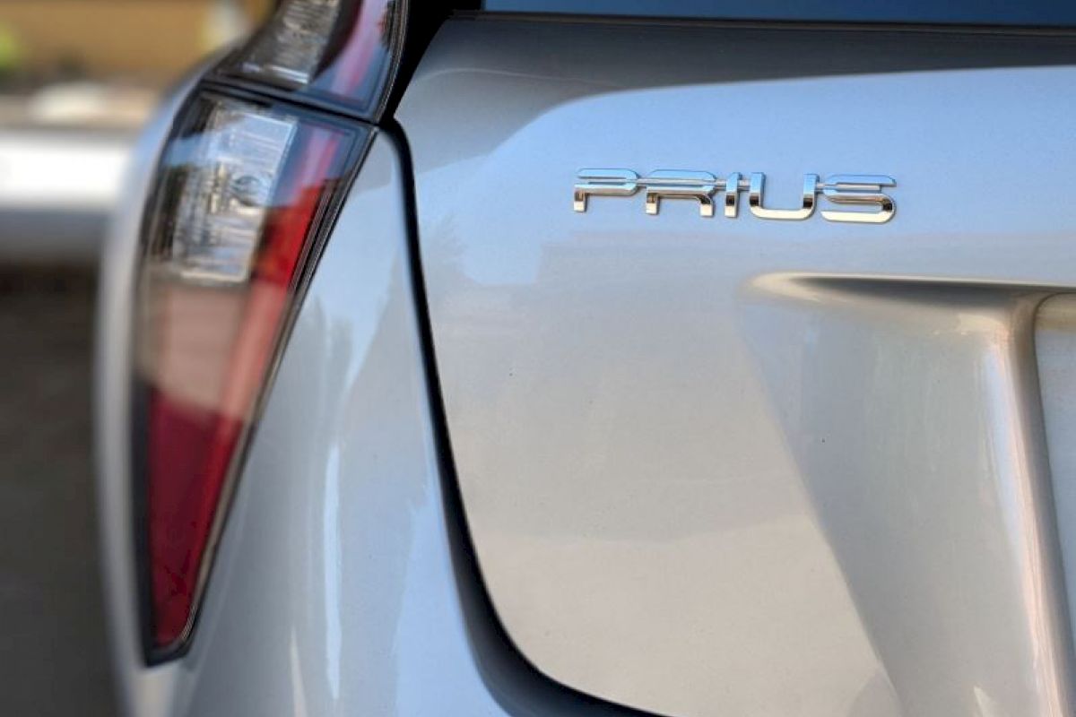 The image shows the rear end of a silver Toyota Prius car, focusing on the taillight and the 